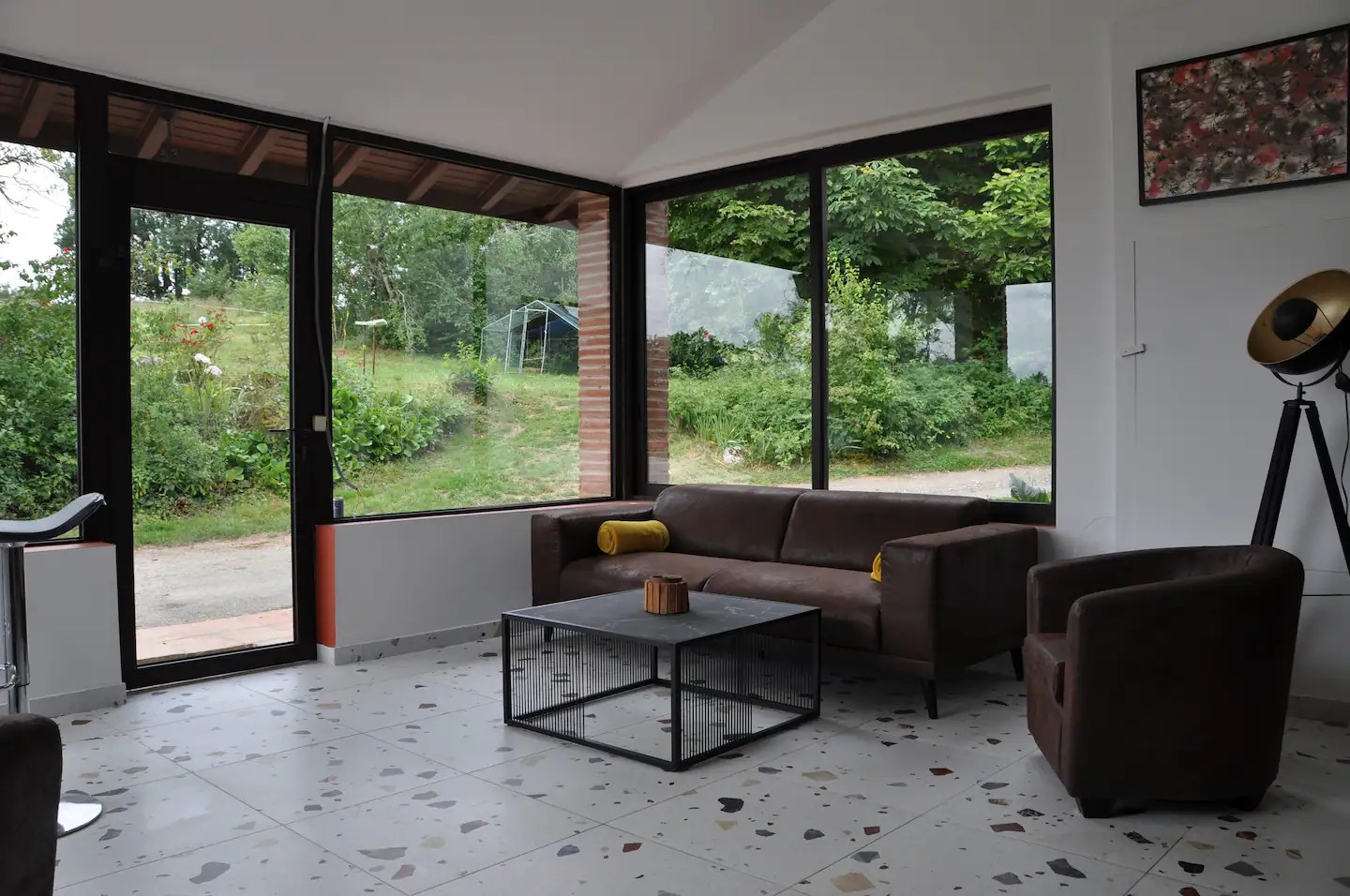 Salon-salle à manger cosy ouvert avec de grandes baies vitrées donnant vue sur le jardin